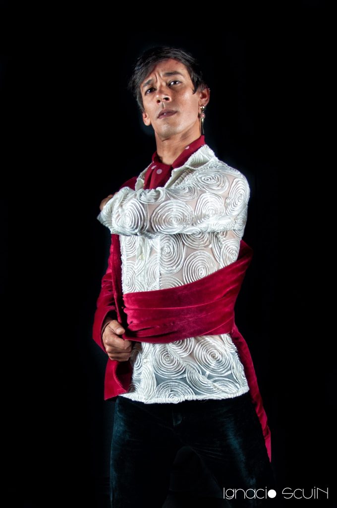 El Mawi de pie con camisa blanca y fajín rojo